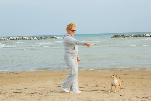 köpeğiyle plajda oynayan kadın